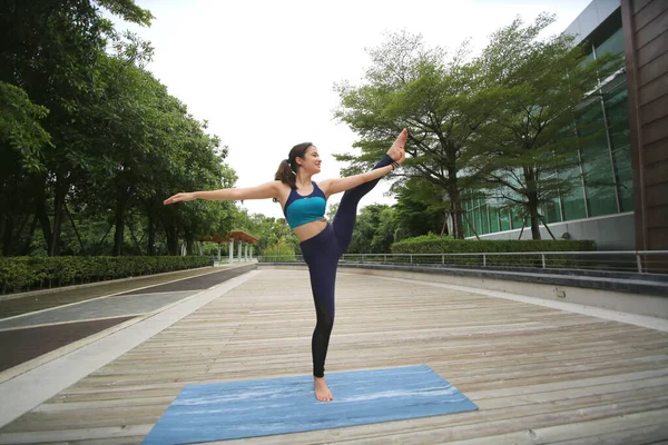Young sporty attractive woman practicing yoga, doing yoga exercise, Beautiful young woman practicing yoga on wooden terrace.