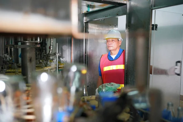 içecek endüstrisinde üretim hattını kontrol eden işçiler.