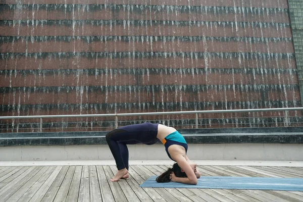 Young attractive woman doing stretching yoga exercise in the park.