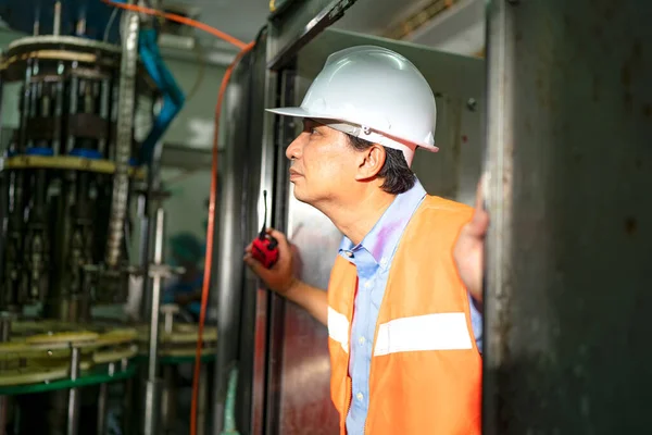 worker controlling the work of machine in production line at beverage industry.
