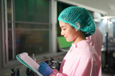 Asian worker labor working in food and beverage for drink industry factory with hygiene work fruit juice production line inspector staff. Inspect Beverage Process Check Production Line Conveyor