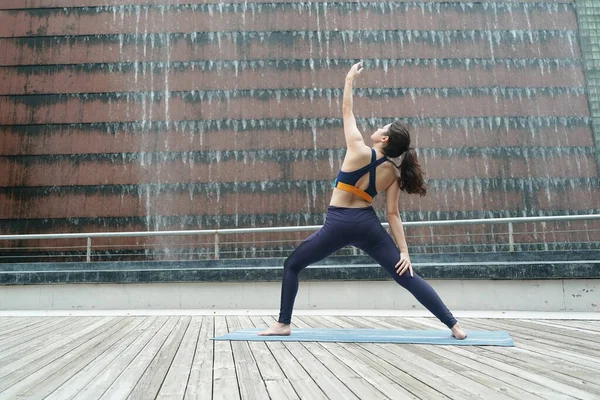 Young attractive woman doing stretching yoga exercise in the park.