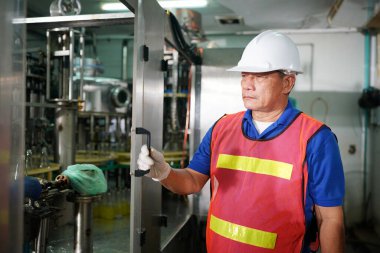 worker controlling the work of machine in production line at beverage industry.