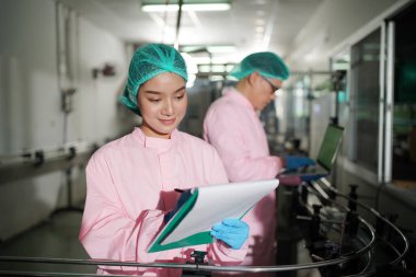 Asian worker labor working in food and beverage for drink industry factory with hygiene work fruit juice production line inspector staff. Inspect Beverage Process Check Production Line Conveyor