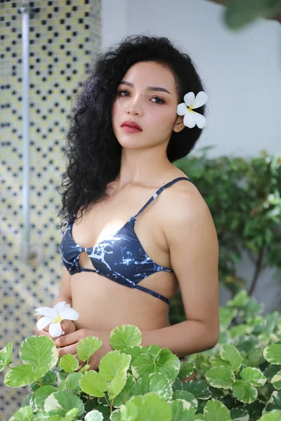 Attractive young woman in sexy bikini at poolside in the outdoor swimming pool, mixed race long hair woman.
