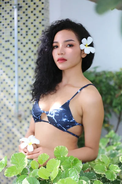 Attractive young woman in sexy bikini at poolside in the outdoor swimming pool, mixed race long hair woman.