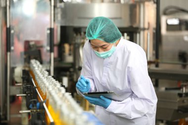 worker controlling the work of machine in production line at beverage industry.