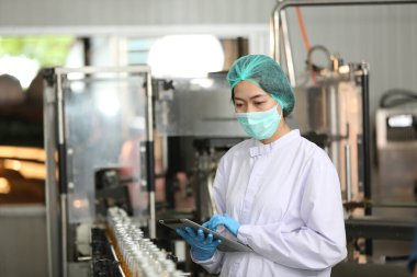 worker controlling the work of machine in production line at beverage industry.