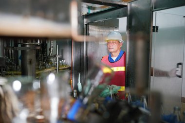 worker controlling the work of machine in production line at beverage industry.