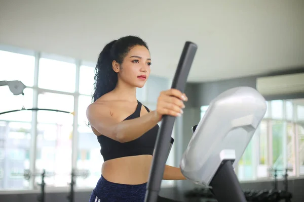 close-up shot of woman working out on elliptical machine at gym