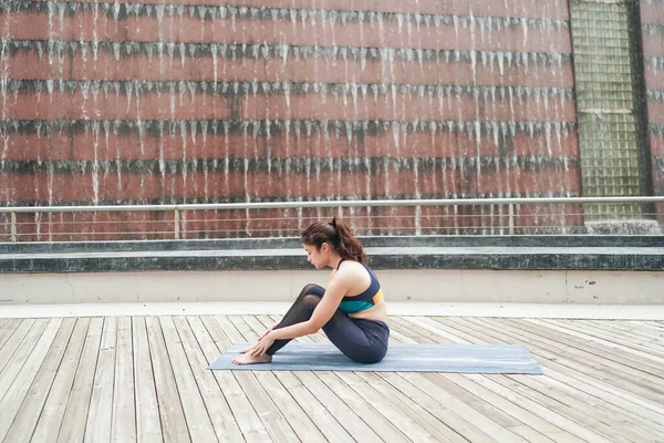 Young attractive woman doing stretching yoga exercise in the park.