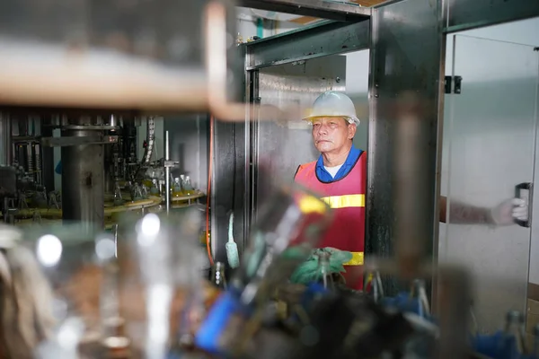 worker controlling the work of machine in production line at beverage industry.