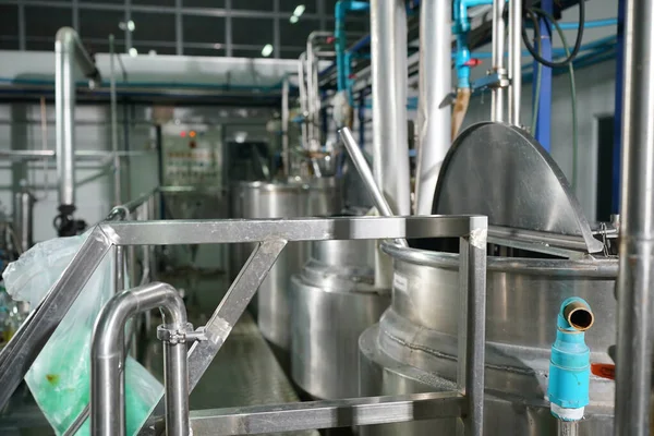 View of reservoires and soft drinks factory interior. worker controlling the work of machine in production line at beverage industry.