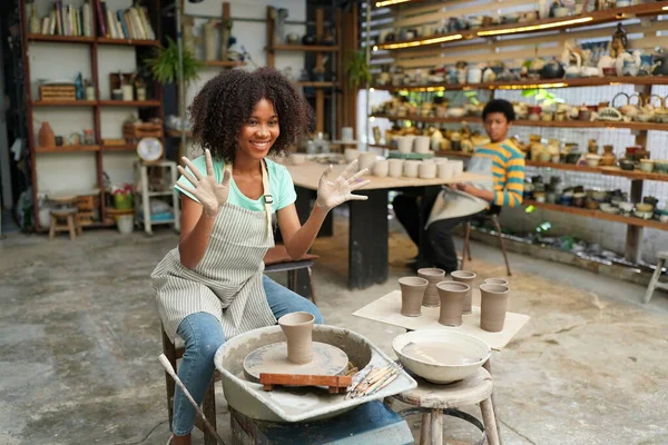 Young Afro girl hand potter making clay vase in pottery workshop, Business owner.