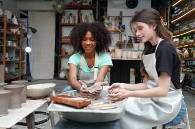 Genç kızlar çömlek atölyesinde vazo yapan çömlekçilere el uzatıyor.. 