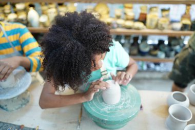 Genç Afro kız çömlekçi çömlekçi çömlek atölyesinde vazo yapıyor, işyeri sahibi.. 