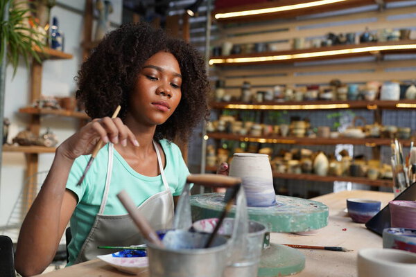 Young Afro girl hand potter making clay vase in pottery workshop, Business owner. 