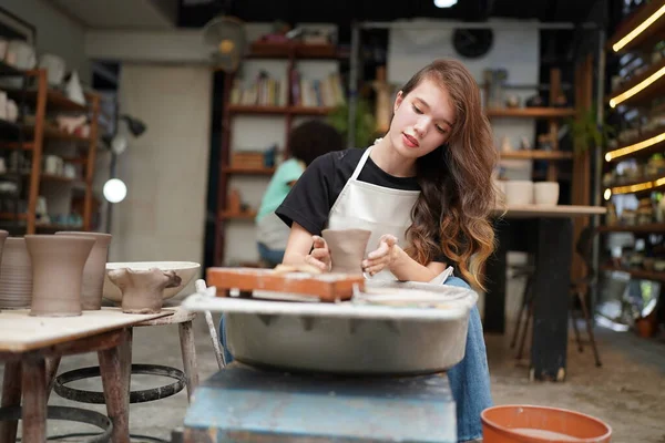 土船を形成しながら 陶器の車輪に座って 工芸品を使用してエプロンに集中した美しい職人のクローズアップ — ストック写真