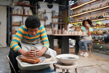 Genç Afro ergen el çömlekçisi çömlek atölyesinde kilden vazo yapıyor.