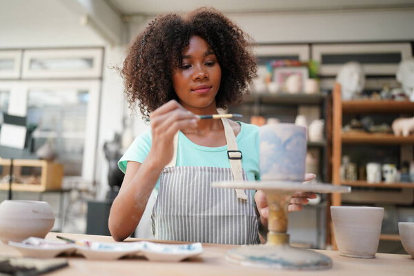Young Afro girl hand potter making clay vase in pottery workshop, Business owner. 