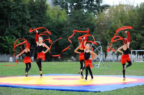 Bir grup küçük artistik jimnastik kızı futbol sahasında kurdelelerle egzersiz yapıyorlar. 20 Haziran 2019 Kiev, Ukrayna