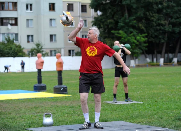 男は芝生の上に立ってケトルベルを燃焼トス ジャグリング 2019年6月20日ウクライナ キエフ — ストック写真