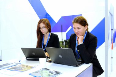 İki gülümseyen bayan ofis çalışanı dizüstü bilgisayarların önünde oturuyor ve çalışıyor. Sergi Silahları ve Güvenlik 2018. 12 Ekim 2018. Kiev, Ukrayna