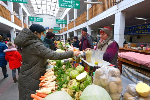 Kvinde køber grøntsager, sælger står bag disken. Det centrale fødevaremarked i Uzhgorod - Stock-foto