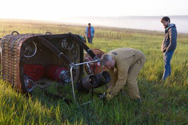 Balon şişirme hazırlıkları: pilot sepeti yere koyuyor, gaz ocakları da yanında. Balon Festivali Pereiaslav-2018. 6 Mayıs 2018. Pereiaslav, Ukrayna