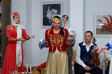 Kırım Tatar geleneksel nikahı: nedimeler bir gelini damat ile buluşmaya hazırlarken kırmızı örtüsünü örterler. Kırım Tatar Kültürü Günleri. 27 Şubat 2019. Kiev, Ukrayna