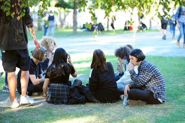 Bir grup genç kız ve erkek şehir parkında çimlerde oturuyor, iletişim kuruyor, rahatlıyor ve sigara içiyor. Andreevsky iniyor. 12 Eylül 2020. Kyiv, Ukrayna