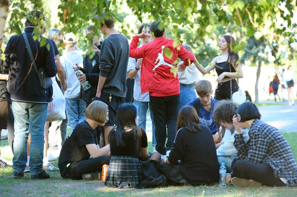 Bir grup genç kız ve erkek şehir parkında çimlerde oturuyor, iletişim kuruyor, rahatlıyor ve sigara içiyor. Andreevsky iniyor. 12 Eylül 2020. Kyiv, Ukrayna