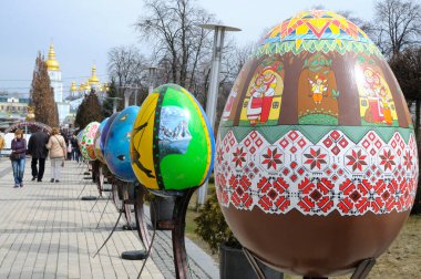 Meydanda büyük boyalı Paskalya yumurtası tesisleri, etrafta dolaşan insanlar. Halk sanatı festivali. 18 Nisan 2018. Kyiv, Ukrayna