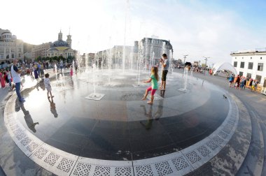Şehirde güçlü bir sıcaklık var: Meydanda fıskiyelerle oynayan gülen çocuklar. 5 Haziran 2018. Kyiv, Ukrayna