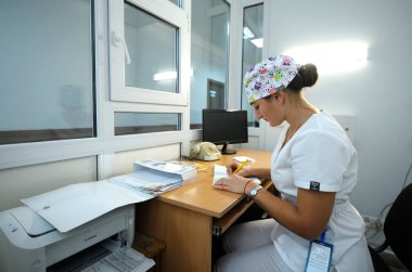 Hastanede görevdeyim. Hemşire hemşire odasında oturuyor ve gazeteye yazıyor. 12 Ocak 2019. Kiev Bölge Kliniği 1. Kiev, Ukrayna