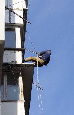 High-altitude installer installing a television antenna on a balcony of an apartment house. Kyiv, Ukraine.