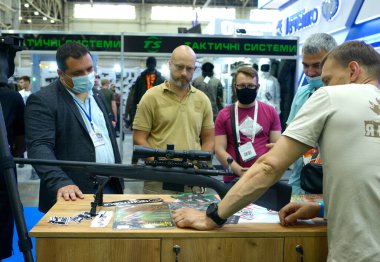 Satış müdürleri silah dükkanının tezgahına yerleştirilmiş yeni spor tüfekleri sundular, alıcılar izliyordu. Silah ve Güvenlik 2021. 15 Haziran 2021. Kyiv, Ukrayna