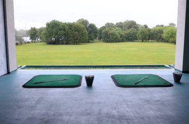 Golf sahası: halılar, golf sopaları ve golf topu dolu sepetler.