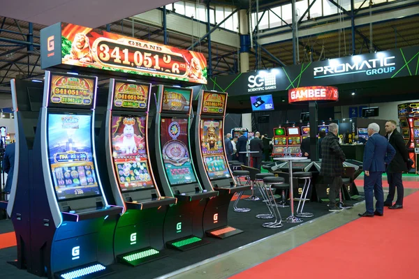 Kumar makinelerinde kumar oynayan ve etrafta dolaşan insanlar. Oyun endüstrisi sergisi. 24 Kasım 2021. Kyiv, Ukrayna