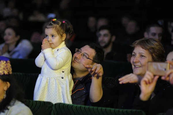 Kırım Tatar kızı konser sırasında sahnede şaşkınlıkla bakıyor, yetişkinler koltuklarda alkışlıyor. Nowruz 'u kutluyoruz. 24 Aralık 2017. Kyiv, Ukrayna