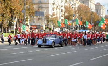 Crowd of teens girls in red costumes and tambores in hands marching on the street. August 18, 2012. Kyiv, Ukraine