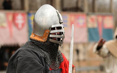 Reenactor man dressed in armor of an Old Rus footman reconstructing sword fight, wooden fortress on a background. Kyiv, Ukraine
