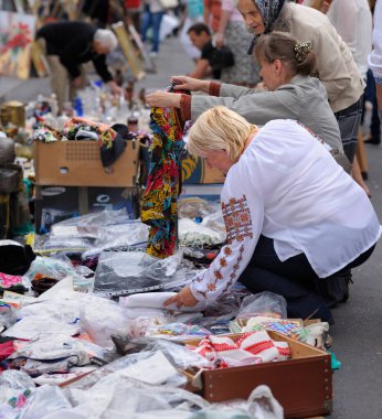 Women choosing handmade clothes placed on a pavement, street fair. August 24, 2013. Andreevsky descent. Kyiv, Ukraine