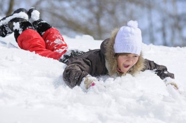 little laughing girl playing in snowdrift fooling around, city park. January 29, 2012. Kyiv, Ukraine