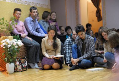Krishna parishioners sitting on a floor and reading mantra from the book. April 3, 2013. Kyiv, Ukraine