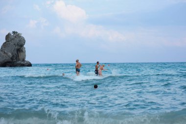 People swimming in the sea, rock cloudy blue sky. June 10, 2017. Gurzuf, Crimea