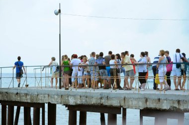 Group of people tourists standing on a pier waiting for an excursion boat. June 10, 2017. Gurzuf, Crimea