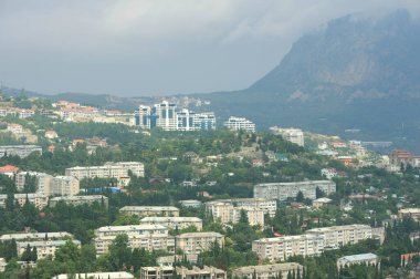 Resort town Gurzuf, buildings beach sea mountains plunged in a fog, cloudy sky, landscape. Southern coast of the Black Sea, Crimea.