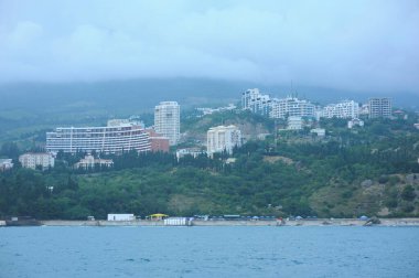 Resort town Gurzuf, buildings beach sea mountains plunged in a fog, cloudy sky, landscape. Southern coast of the Black Sea, Crimea.