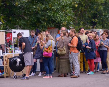 İnsanlar tezgahın önünde sıra bekliyor, adam satıcı sokak yemeği satıyor. 3 Haziran 2018. Kyiv, Ukrayna